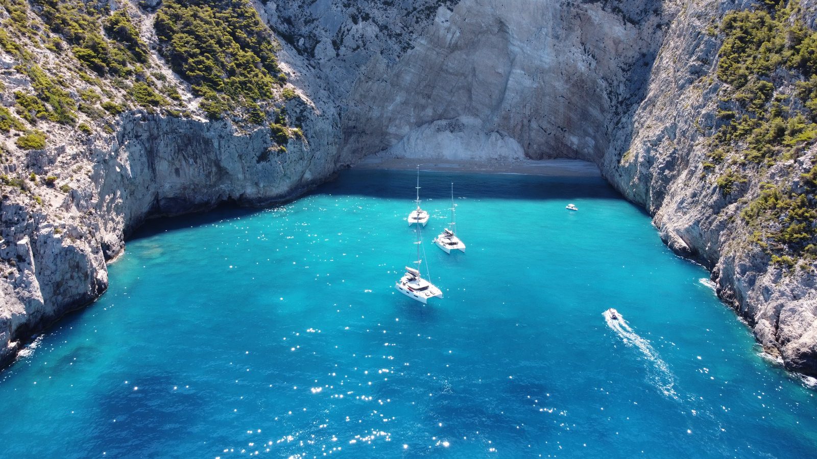 Yachts anchored in a cove walled by white limestone cliffs, west coast of Zakynthos