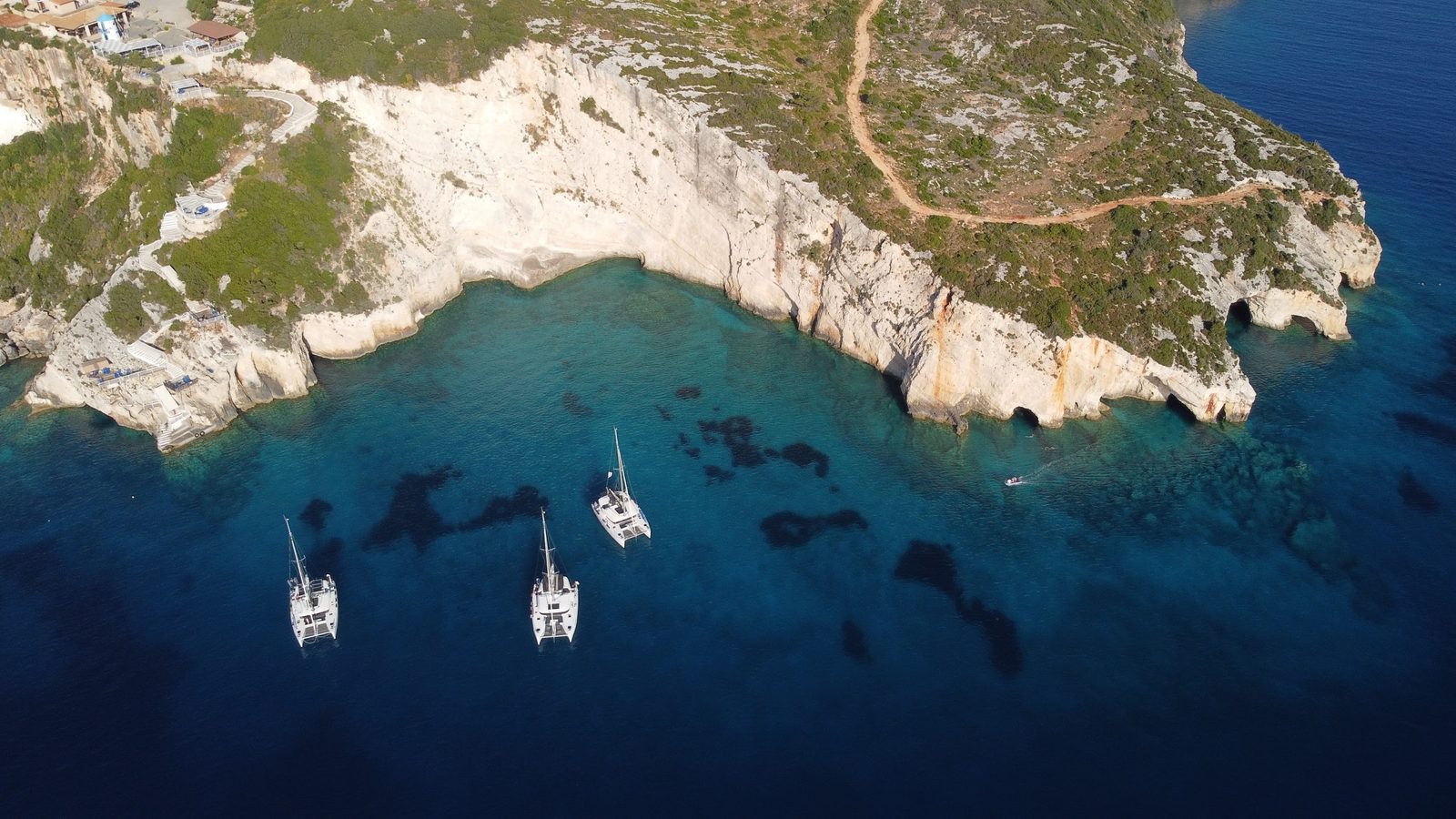 The white cliffs of the Skinari cape from the air, yachts anchored below the caves