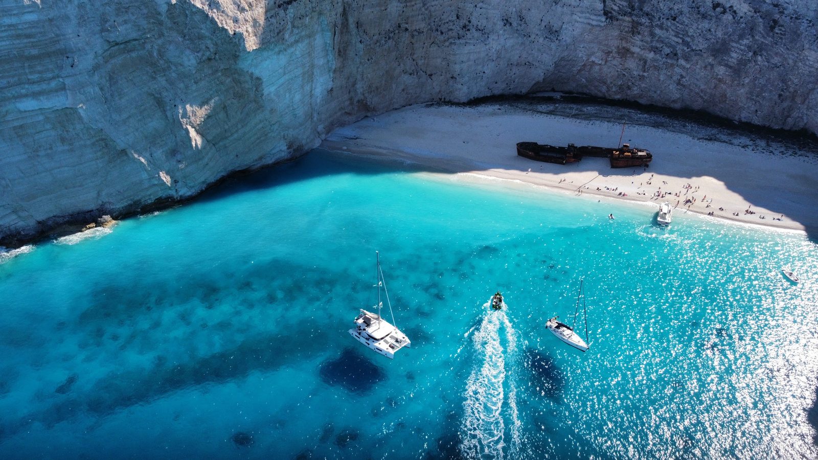 Navagio beach from the air: the shipwreck on the white sand, yachts in the turquoise bay