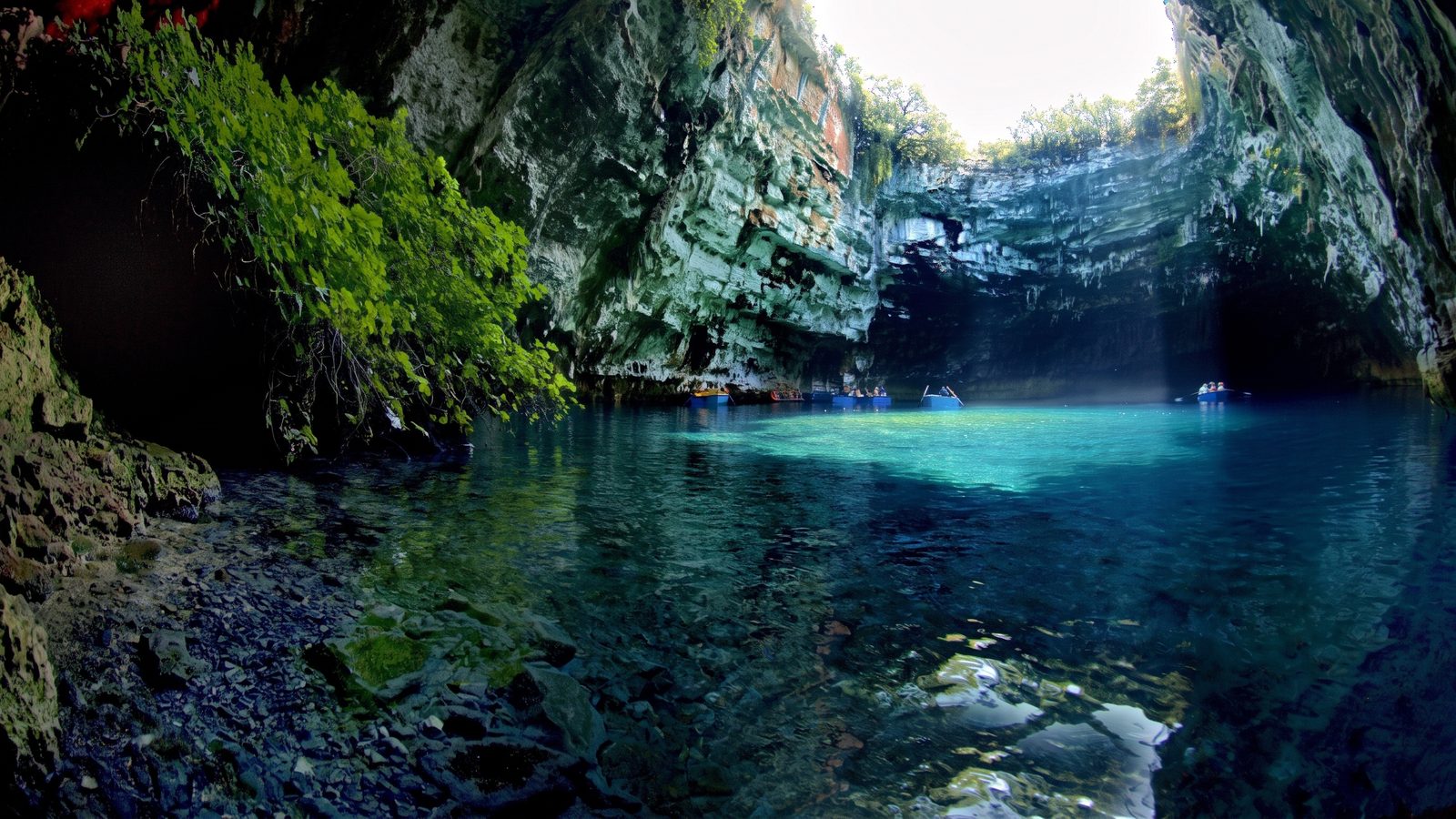 Inside the Melissani cave: rowing boats on the clear lake under the collapsed roof