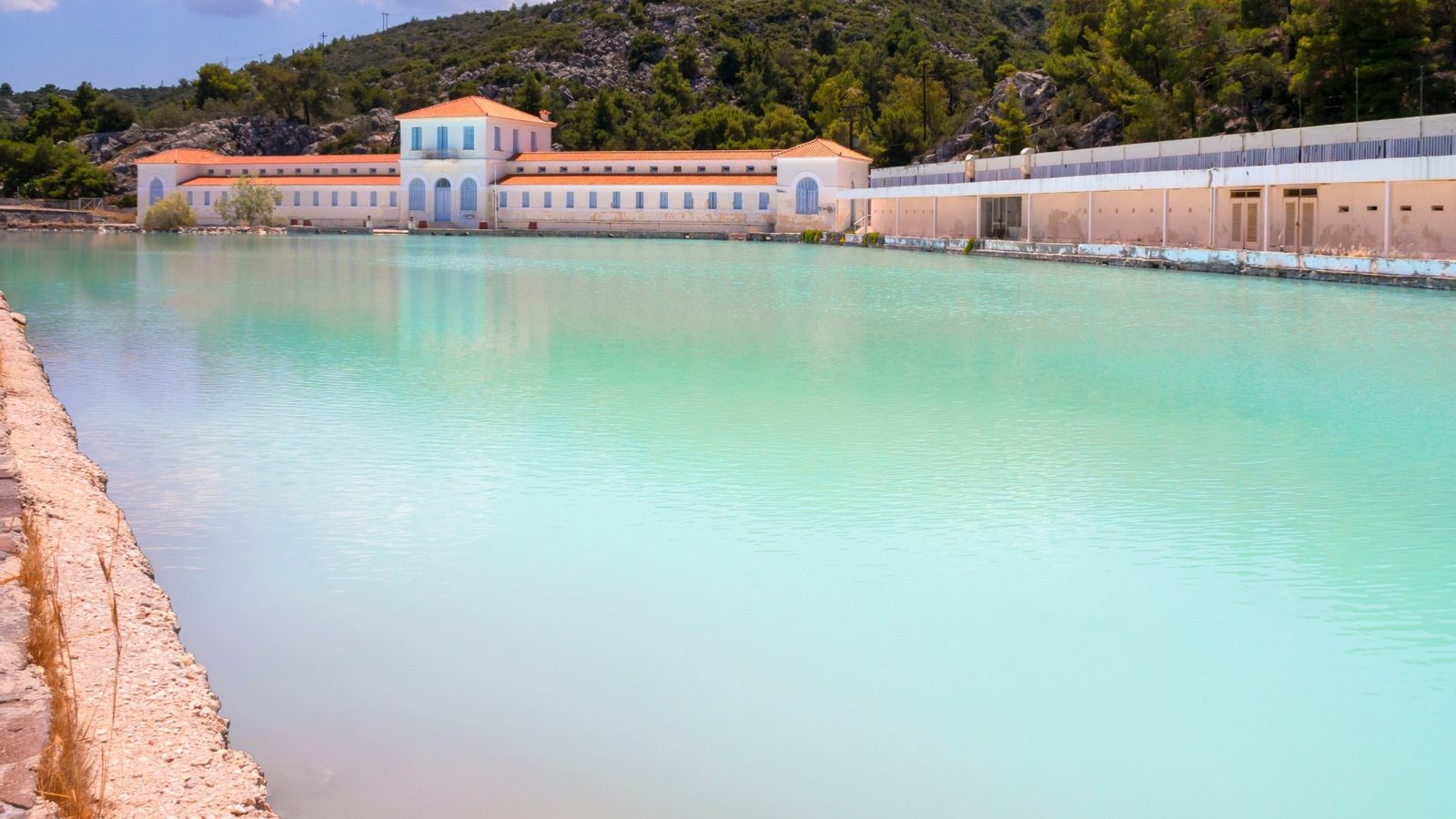 The old thermal baths of Methana: milky turquoise sulphur pool under the hills