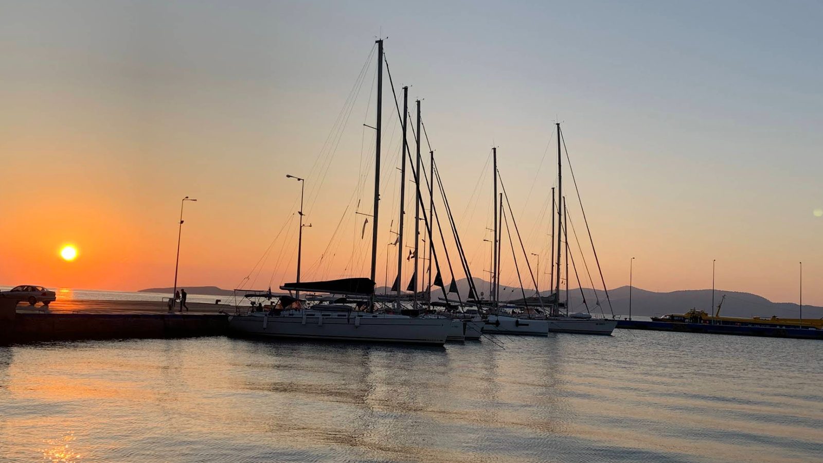 Sunrise over the sea at Methana, yachts stern-to on the quay