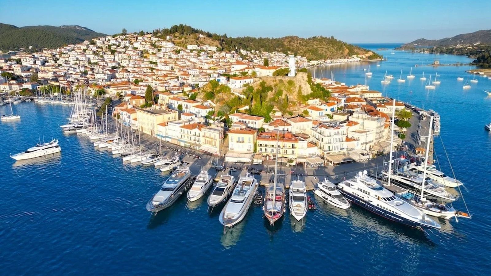 Poros town from the air: the clock tower on the hill and yachts along the quay