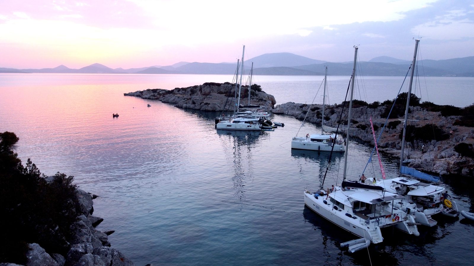 Catamarans anchored among bare rocks at dusk