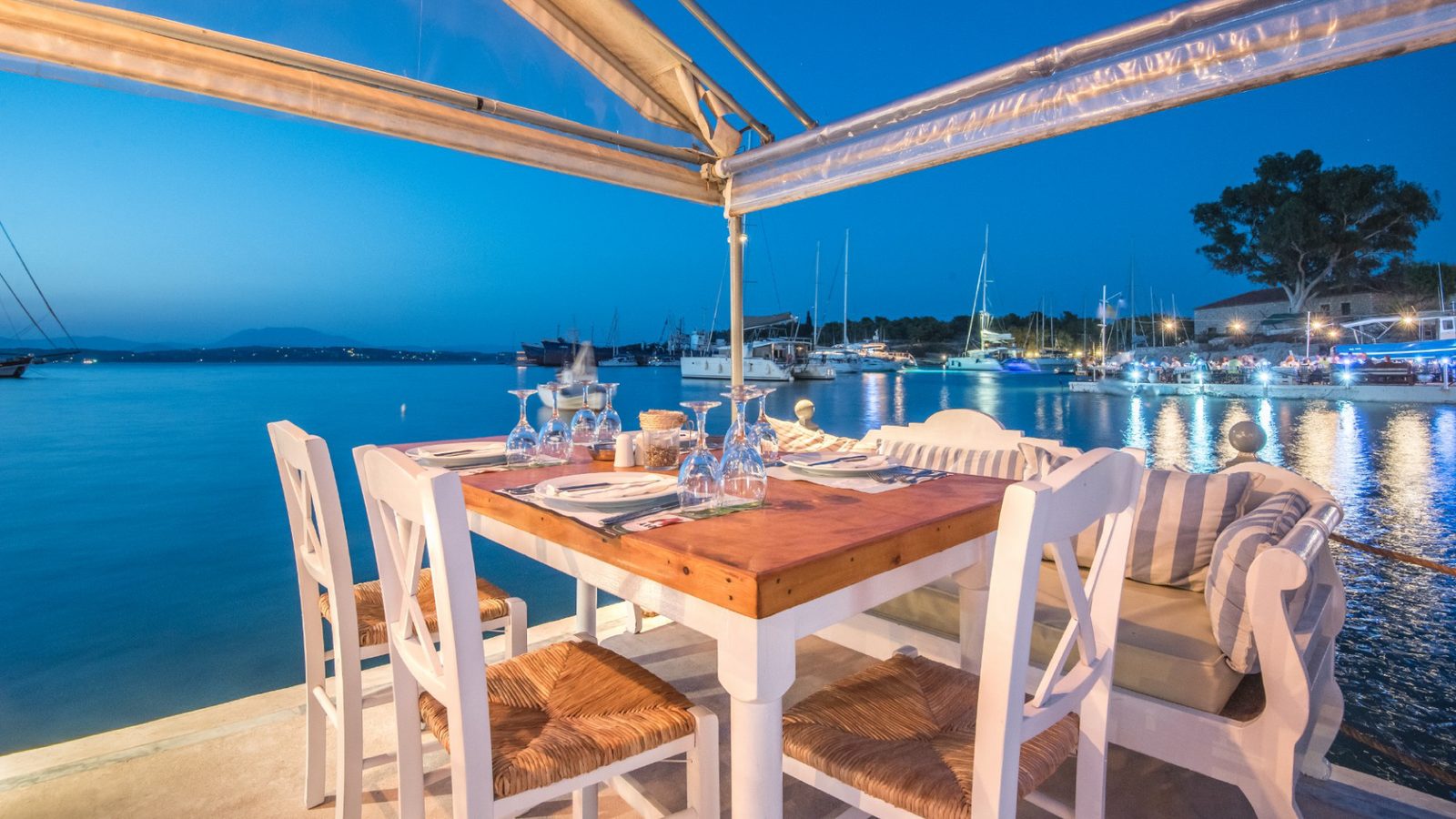 A table set for dinner over the Old Harbour, boats lit up at night