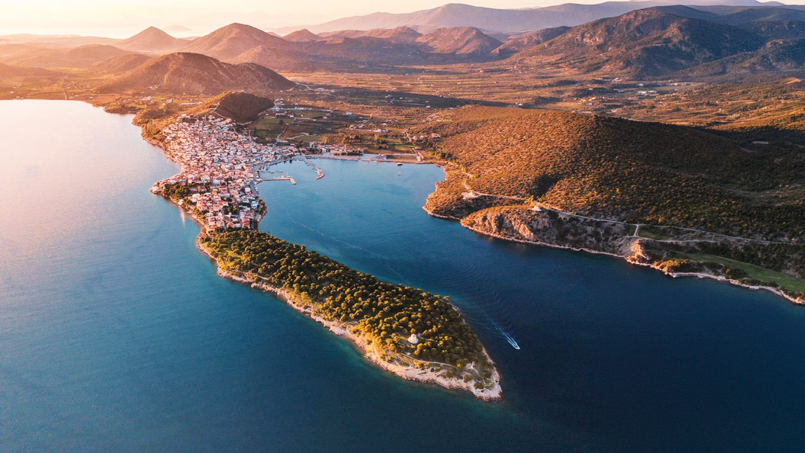 Ermioni&rsquo;s pine-covered peninsula from the air at sunset, a harbour on each side